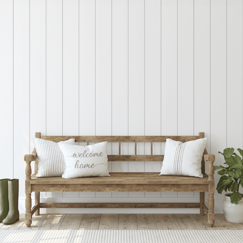 Illustrating the organization idea of the usefulness of a bench in the entryway. A wooden bench with three pillows in the entryway of a home.